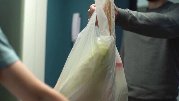 特写的快递男子送的袋子与健康食品的女人客户在家门口的公寓