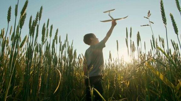 日落时分一个男孩在田野里玩飞机