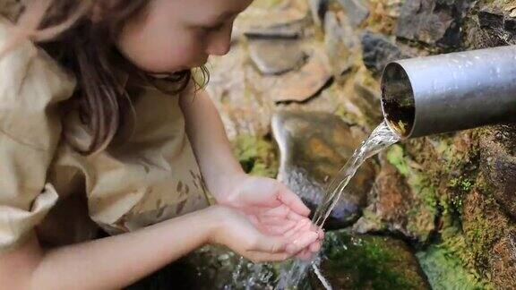 小女孩在大自然中喝干净的泉水山区饮用水源