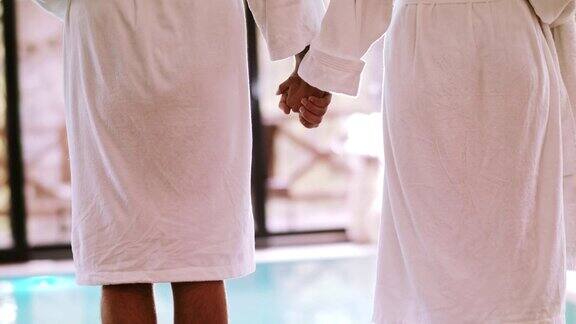 一对夫妇在泳池边手牵着手