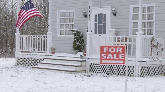 在隆冬季节在被雪覆盖的院子里大型独栋房屋前的房产标识正在出售аnd下雪了