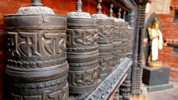 尼泊尔加德满都杜巴广场的寺庙院子里一排古老的祈祷轮或鼓上面有咒语“唵摩尼?帕德美”西藏佛教