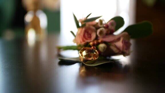 特写的两个金婚戒躺在花瓣上的玫瑰背景