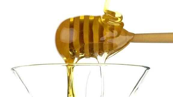 玻璃碗与蜂蜜和木棒勺在白色的背景