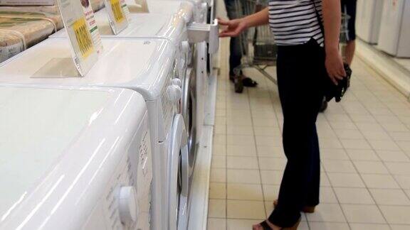 在白色家电店里选购洗衣机的女人