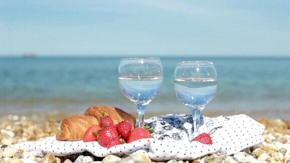 海滩上的早餐一杯水草莓和牛角面包近距离