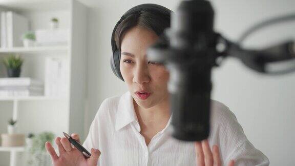 年轻的亚洲妇女在她的笔记本电脑从家庭工作室录制播客