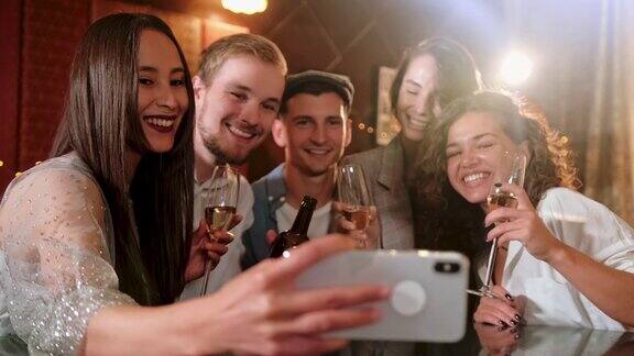 年轻开朗的女性朋友在酒吧用手机自拍朋友男人女人休闲友谊和科技概念-朋友与智能手机在酒吧或酒吧喝啤酒