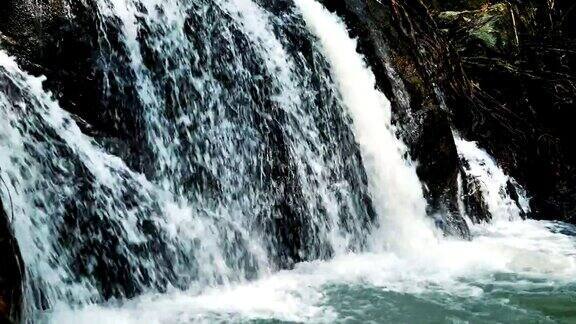 泰国野生丛林森林环境中美丽的瀑布自然风景慢镜头旅行和冒险的观点人们走向瀑布