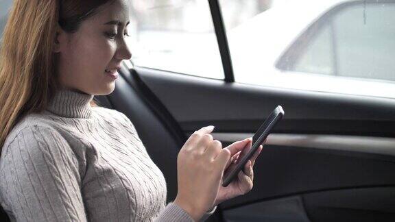 亚洲女性在车里用智能手机进行社交媒体