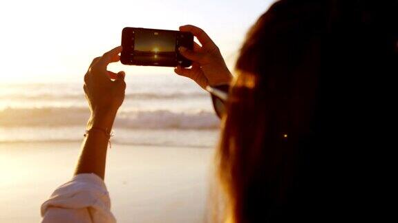 女人在沙滩上用手机拍照