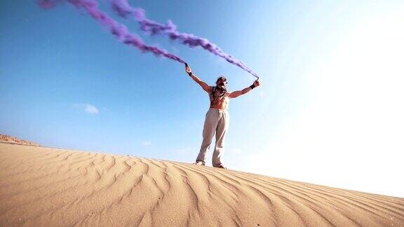 一个年轻人拿着烟雾弹站在沙漠里