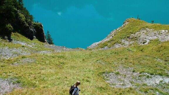 一个金发女孩在瑞士阿尔卑斯山脉的oeschinen湖徒步下山背景是蓝山湖