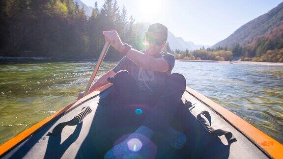 一个年轻人在山腰的湖上划独木舟