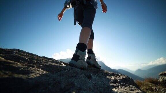 徒步旅行者沿着岩石顶部爬伸展手臂