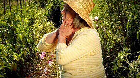 一位上了年纪的妇女跪在花园里使劲地干活还揉着脖子