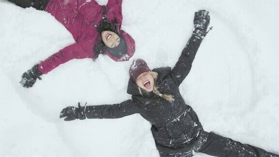 两个年轻漂亮的女人躺在雪地上堆着雪天使