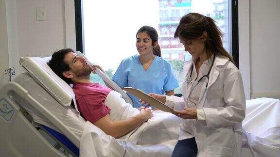 医生在检查住院病人一边和病人谈话一边查看病历护士站在病人旁边