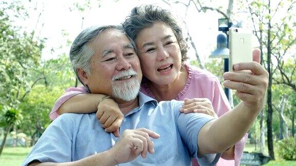 亚洲夫妇老年人一起在公园放松用智能手机和朋友视频通话的老人人们生活方式