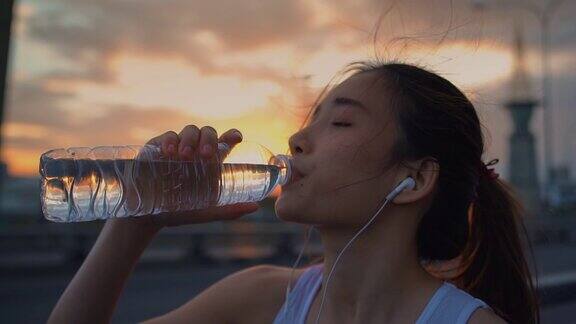 年轻的亚洲女运动员在跑步后喝水特写