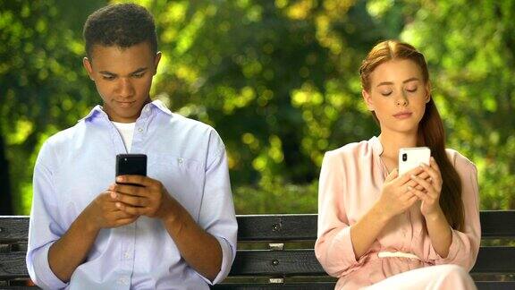 男女青少年坐在长椅上用智能手机聊天问题