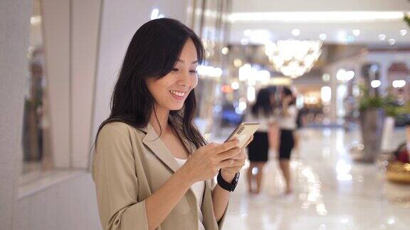 亚洲女性在购物中心使用智能手机