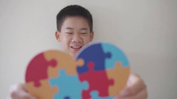 少年手拿拼图拼图心形学龄前儿童心理健康概念世界自闭症意识日自闭症谱系障碍意识概念