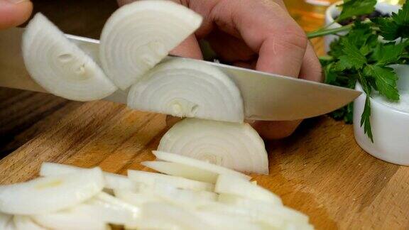 手用刀在厨房板上切洋葱在家做饭