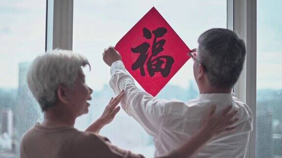 中国新年老夫妇装饰房子的客厅窗户上的中国书法装饰准备家庭团聚