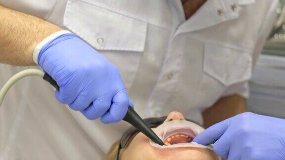 牙医在现代牙科诊所里治疗病人牙齿矫正医师有一个助手运行中采用围堰客户正在做假牙医生和助手戴着防护口罩工作