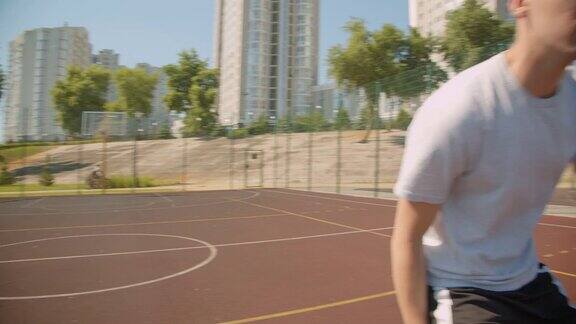 年轻有吸引力的白人男性篮球运动员的特写在公园的球场上扔一个球在篮筐里