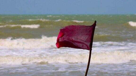 红旗是危险和禁止游泳的象征在狂风中迎风飘扬背景是波涛汹涌的大海