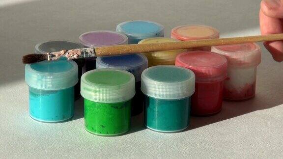 一位艺术家从一罐丙烯酸水粉颜料中拿出一支画笔