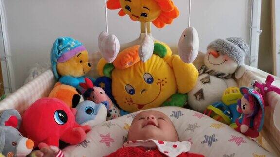 微笑的婴儿看着她的玩具笑着看着玩具旋转三个月大的女婴在床上玩耍COVID-19大流行期间的新生儿