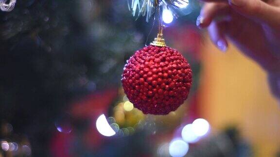 女人的手在圣诞树上挂了一个圣诞球