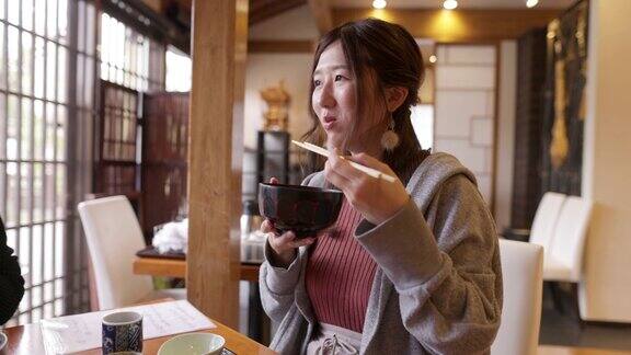 年轻女性在日本餐馆吃“DonabeGohan”健康的日本食物