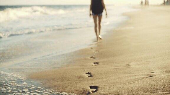 少女走在沙滩旁边的水边与近距离飞机的腿和脚印