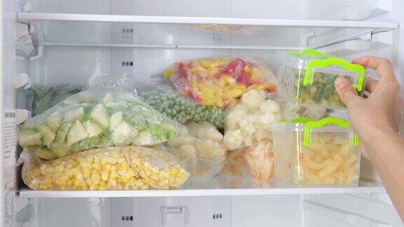女汉兹把装有冷冻蔬菜的容器放进冰箱冷冻水果蔬菜肉类在冰箱里