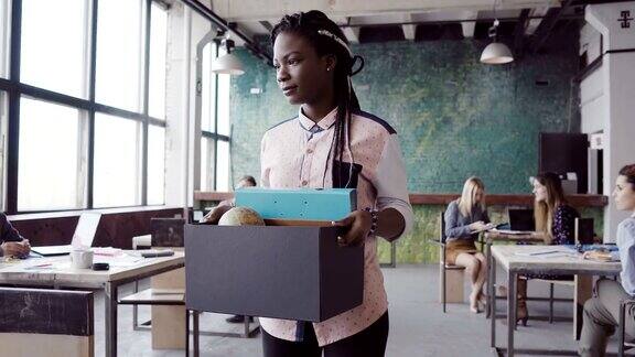 年轻的非洲女人被解雇了一名女性拿着装有个人物品的箱子走过办公室