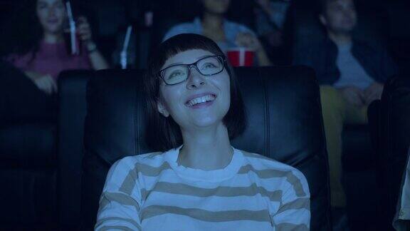 戴着眼镜的迷人女人在电影院和一群人一起欢笑