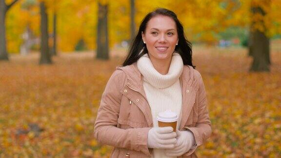 在秋天公园喝外卖咖啡的女人