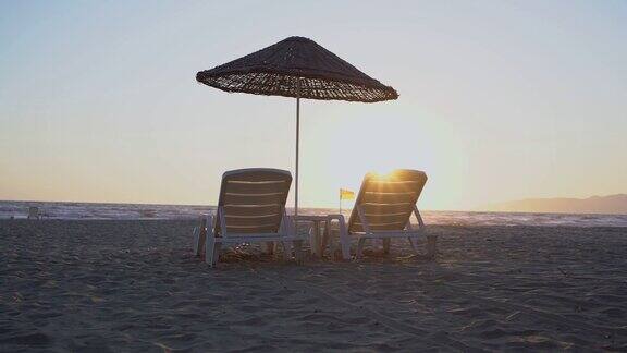 海边沙滩上的白色塑料伞下的躺椅
