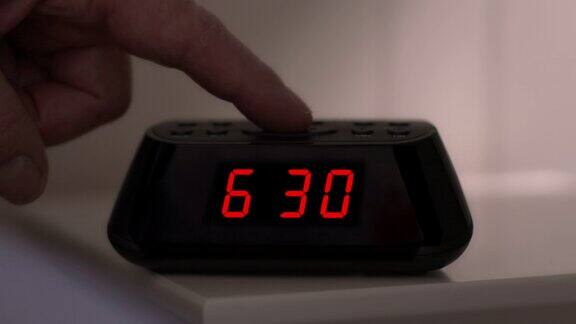 关掉一个数字闹钟时间从6点29到6点30男人的手