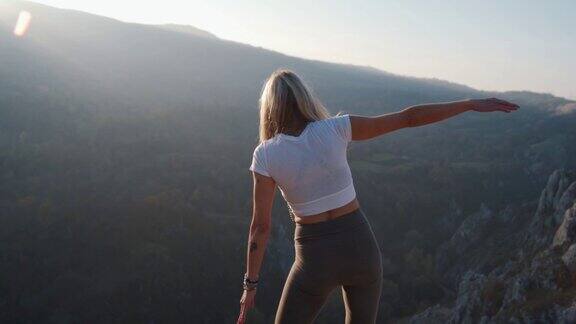 一名女子只站在山顶上练习瑜伽树式