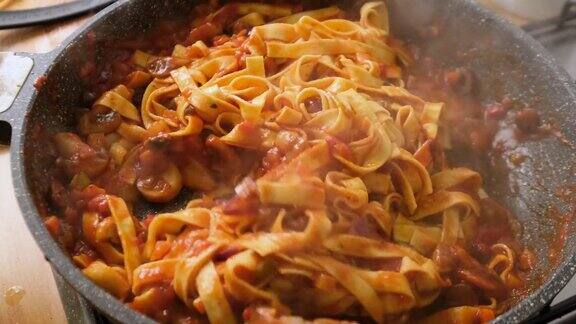 搅拌和烹饪通心粉番茄酱橄榄和蘑菇