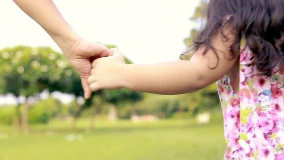 亚洲家庭在公园里母女手牵着手走在一起