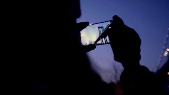 女游客用智能手机拍摄日落