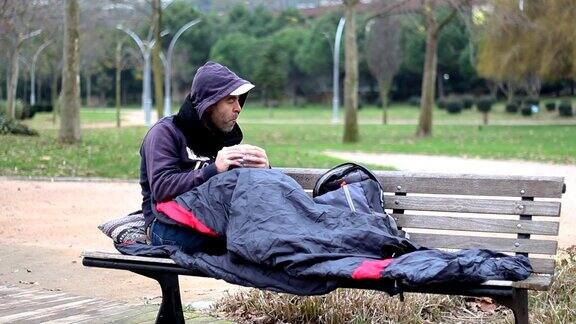 一个无家可归的人在公园的长椅上吃零食