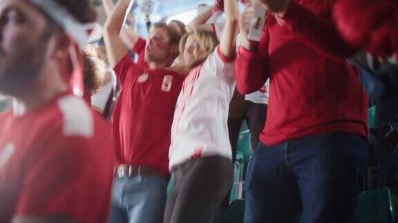 体育场大事件:大批球迷为红色足球队的胜利欢呼人们庆祝进球冠军胜利可爱的白种人夫妇与画的脸欢呼呼喊