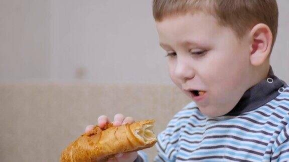 快乐的男孩吃着羊角面包竖起大拇指